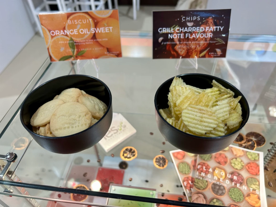 Échantillons de biscuits à l'orange et chips grillées dans bols noirs sur présentoir en verre