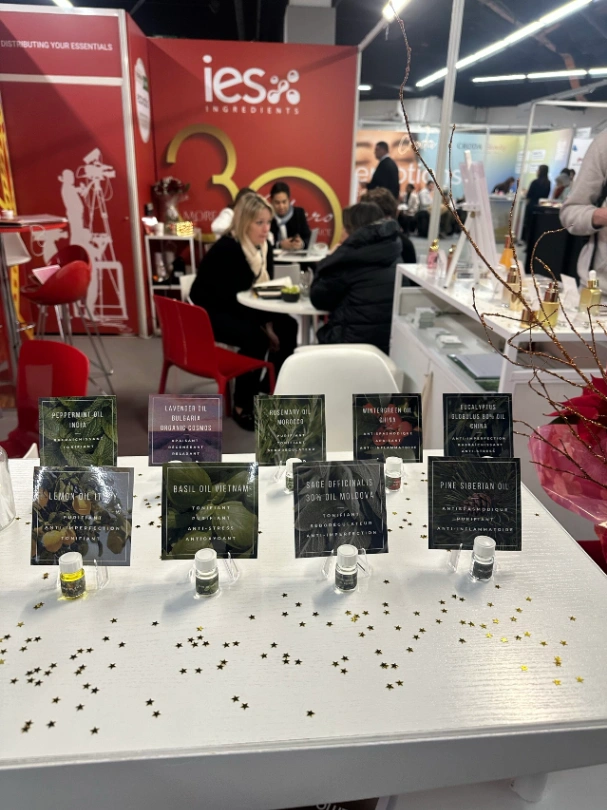 Stand IES Ingredients avec échantillons d'huiles essentielles exposés sur table blanche lors d'un salon professionnel
