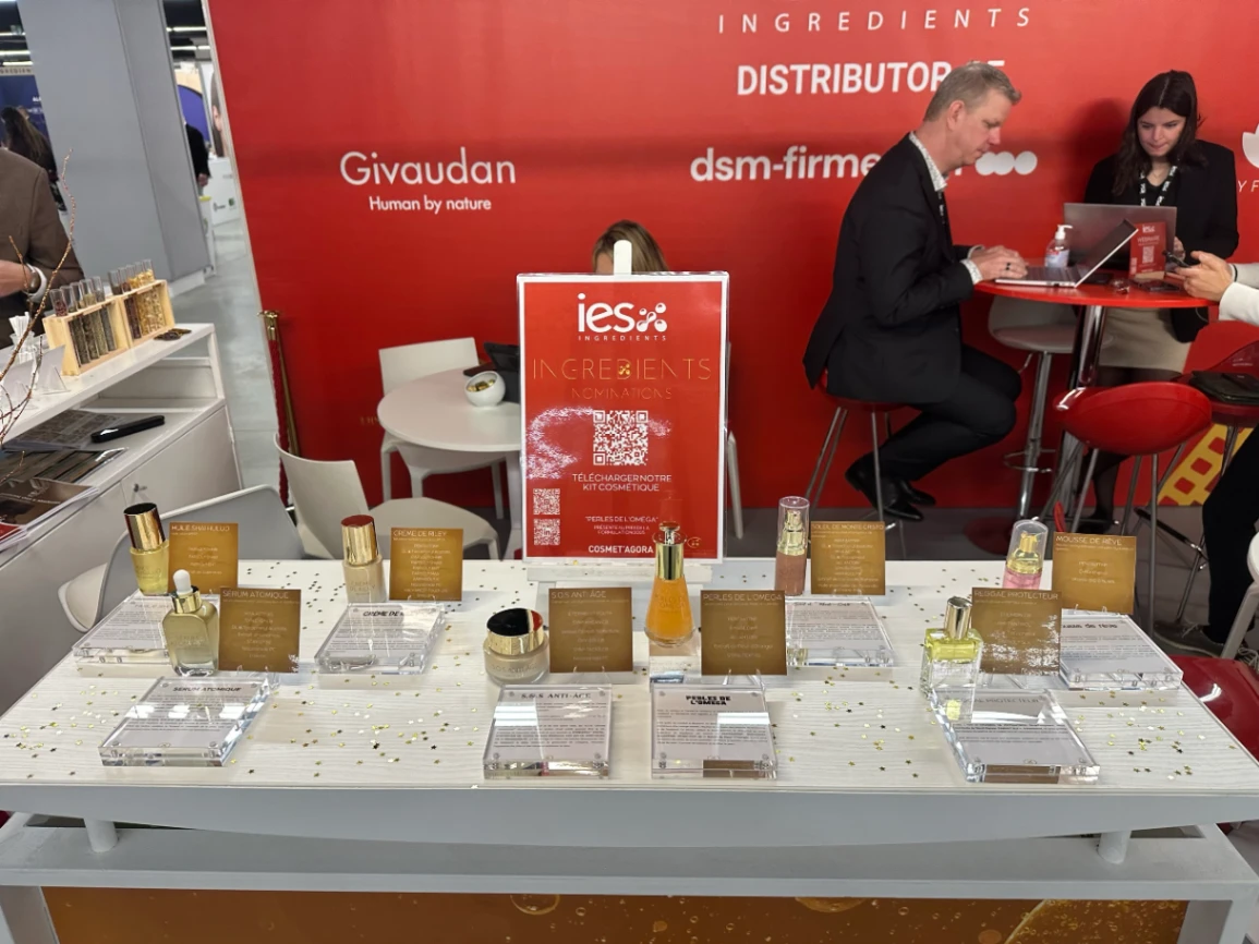 Stand IES Ingredients salon cosmétique avec produits exposés et visiteurs en arrière-plan