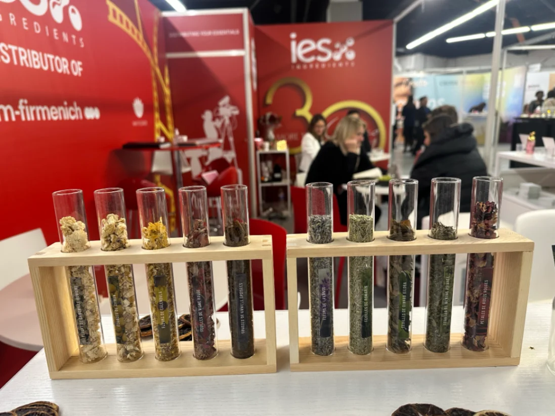Tubes à essai contenant différents ingrédients naturels exposés sur stand IES au salon professionnel