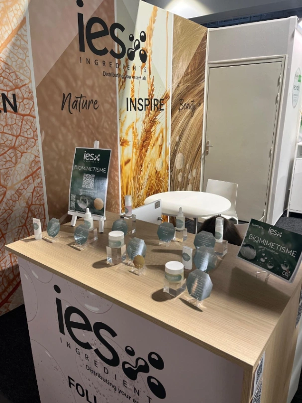 Stand IES Ingredients au salon professionnel avec produits biomimétisme, bannière Nature Inspire Beauty