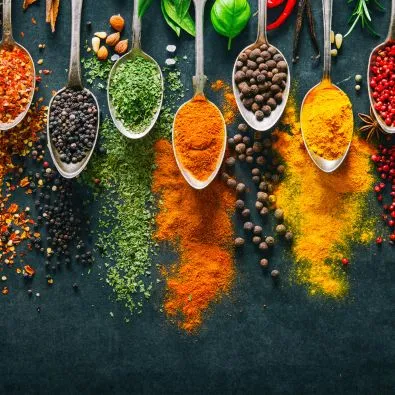 Cuillères contenant épices colorées et ingrédients naturels disposées sur fond sombre