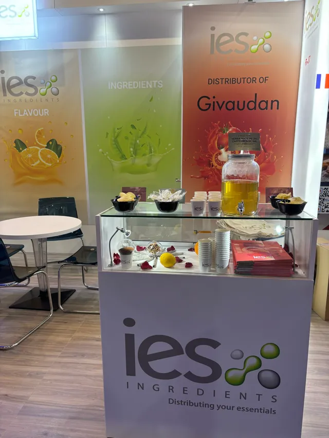 Stand d'exposition IES Ingredients avec bannières colorées et présentoir vitré d'échantillons d'ingrédients naturels
