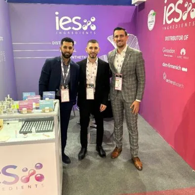 Trois hommes d'affaires posant devant le stand IES Ingredients lors d'un salon professionnel