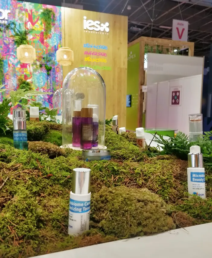 Stand d'exposition cosmétique avec produits de beauté disposés sur mousse verte naturelle