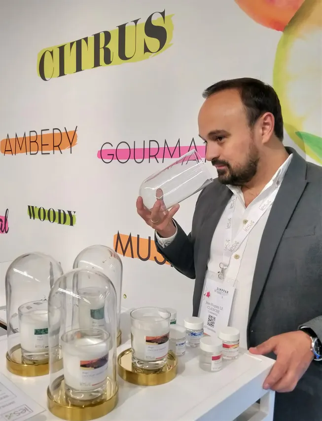 Homme en costume présentant des échantillons d'arômes sous cloches de verre lors d'un salon professionnel