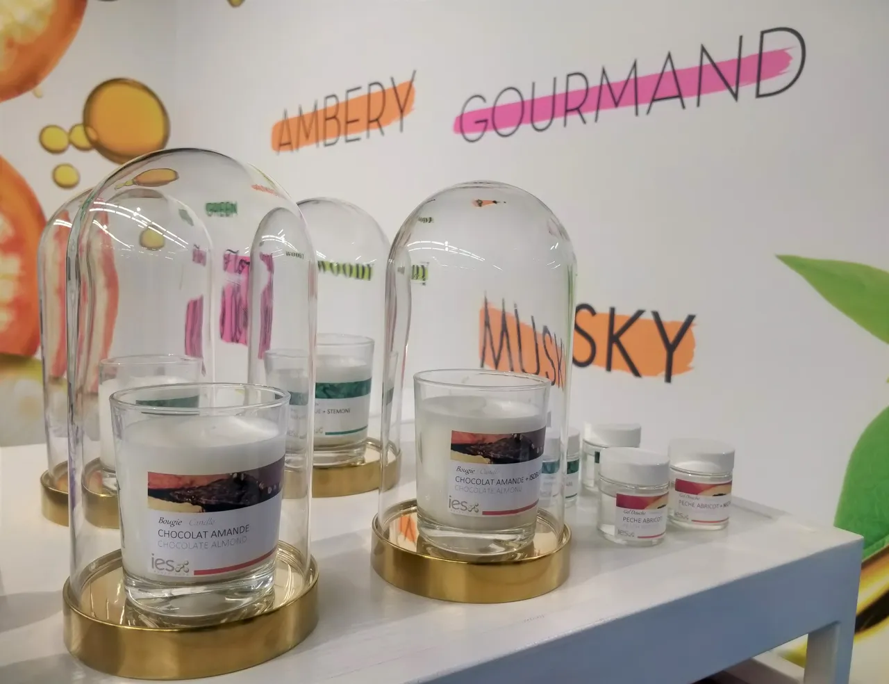 Cloches en verre présentant des ingrédients aromatiques chocolat amande sur présentoirs dorés - stand IES