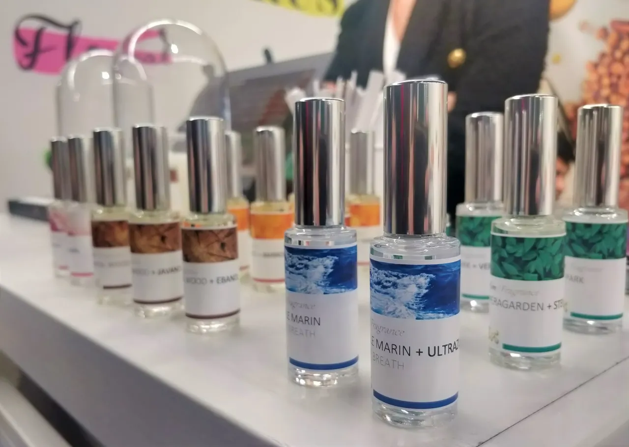 Collection de flacons de parfum aux capsules colorées disposés sur présentoir blanc, ingrédients naturels