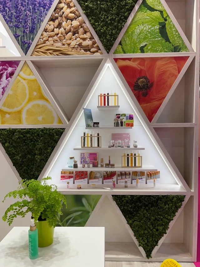 Modern triangular display with cosmetic products and natural ingredients - lavender, nuts, mint, citrus fruits