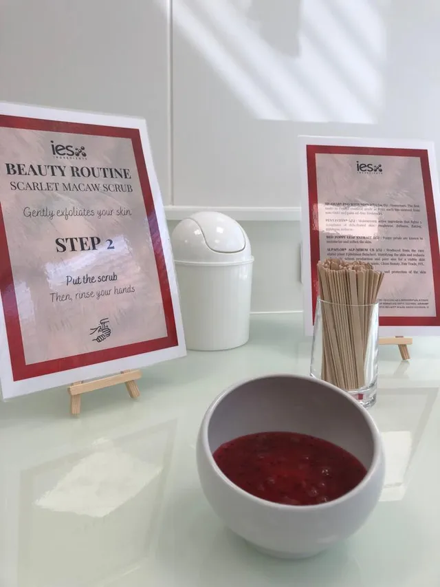 Station démonstration routine beauté IES avec gommage macaw rouge, bâtonnets bois et instructions étape 2
