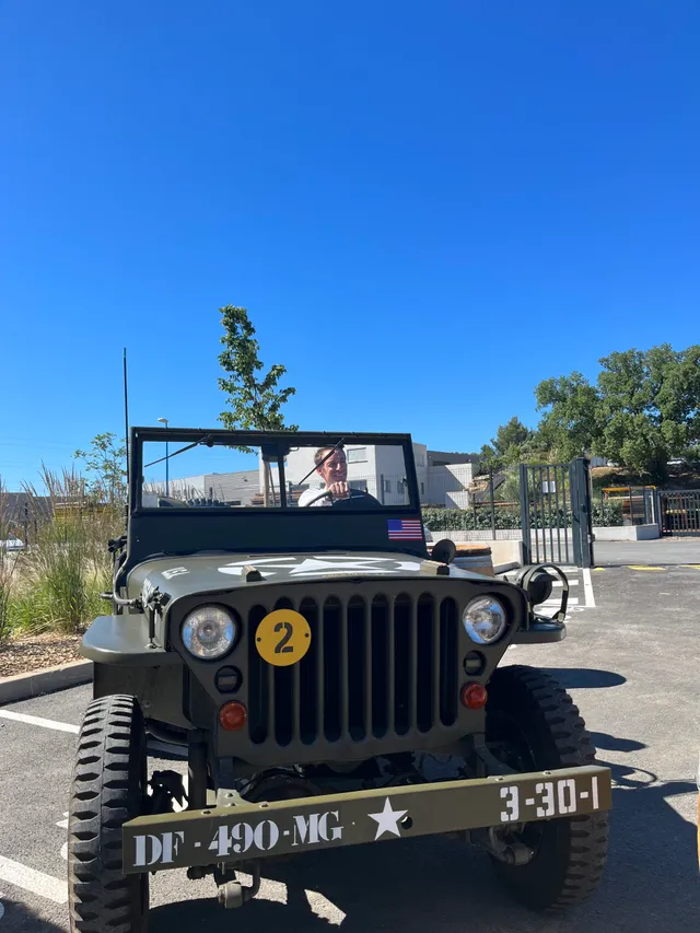 Jeep militaire vintage olive avec marquages DF-490-MG et numéro 2, stationnée sous ciel bleu