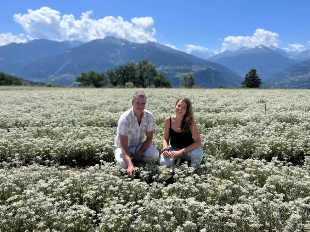 Deux personnes assises dans un champ de plantes aromatiques en fleurs avec montagnes alpines en arrière-plan